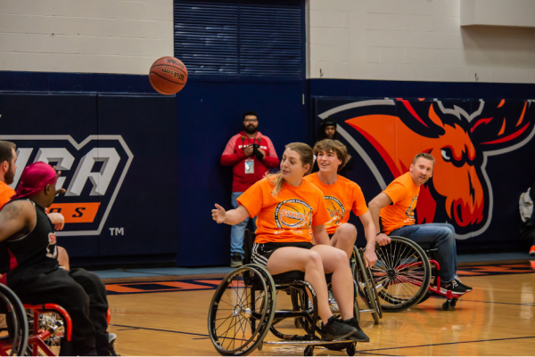 Person in wheelchair on basketball court playing basketball.